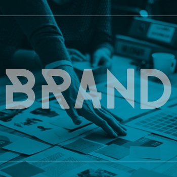 Hand organizing brand materials on a table with the word "BRAND" overlayed