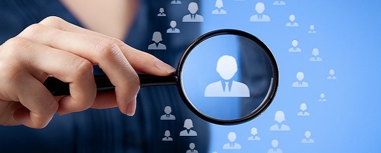 Hand holding magnifying glass focusing on a user icon among many, symbolizing data targeting or customer profiling