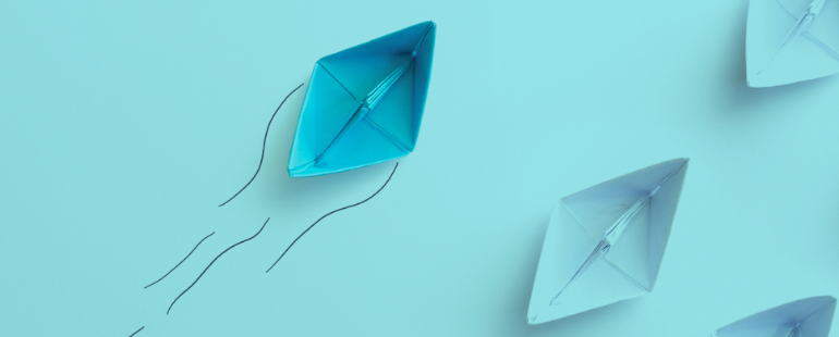 Blue paper boat leading white boats on light blue background