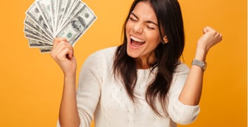 a woma cheering holding a wad of cash