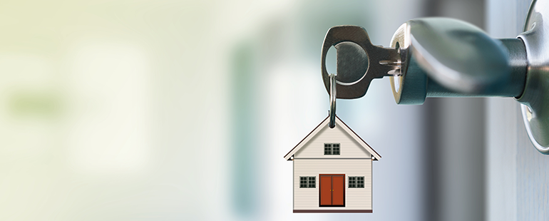 House-shaped keychain hanging from a key inserted in a door lock