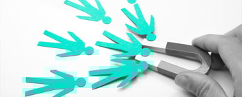 Hand holding magnet attracting paper cutout people, symbolizing customer acquisition and retention through targeted direct mail marketing strategies.