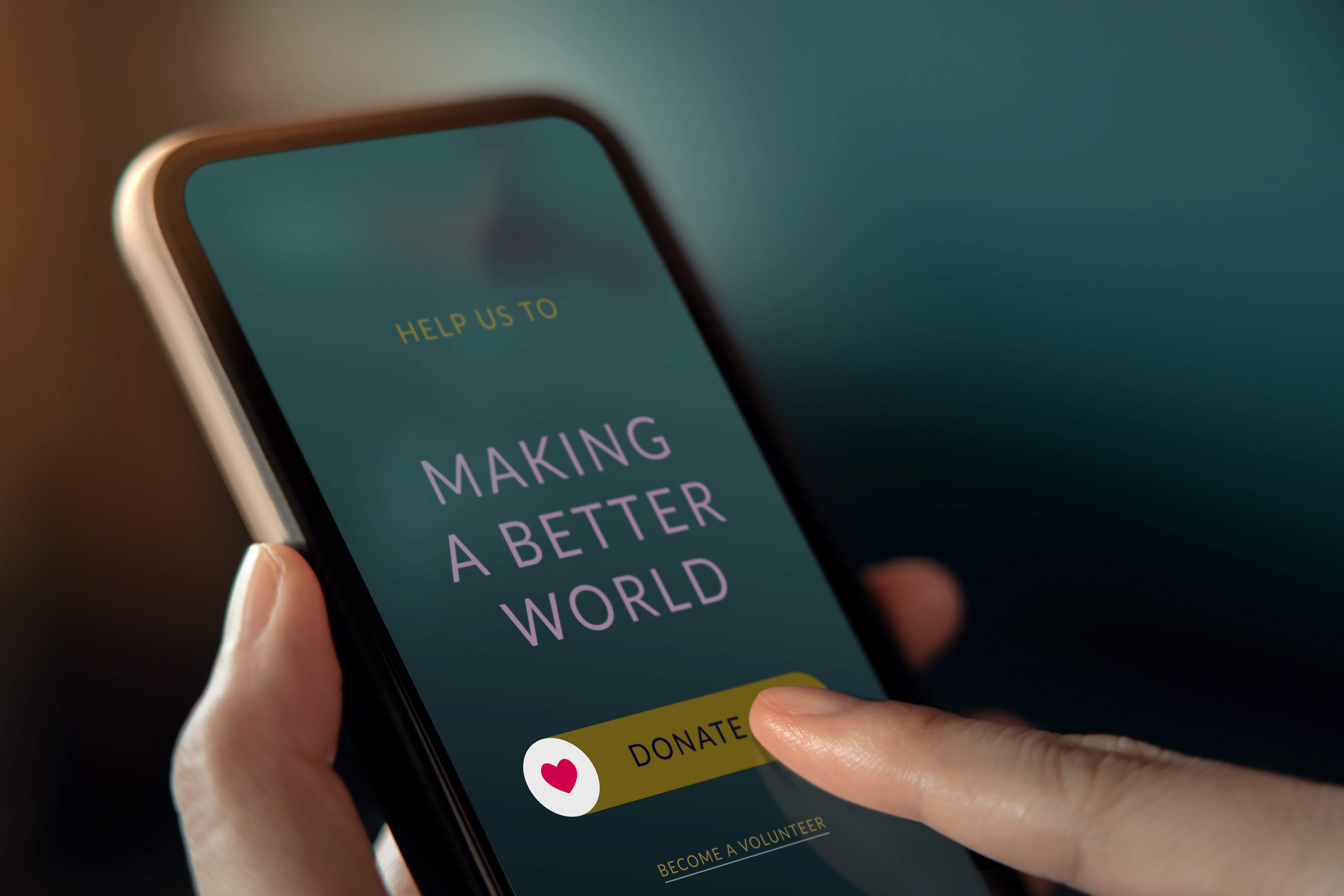 Person tapping a donate button on a smartphone screen with message "Making a Better World"