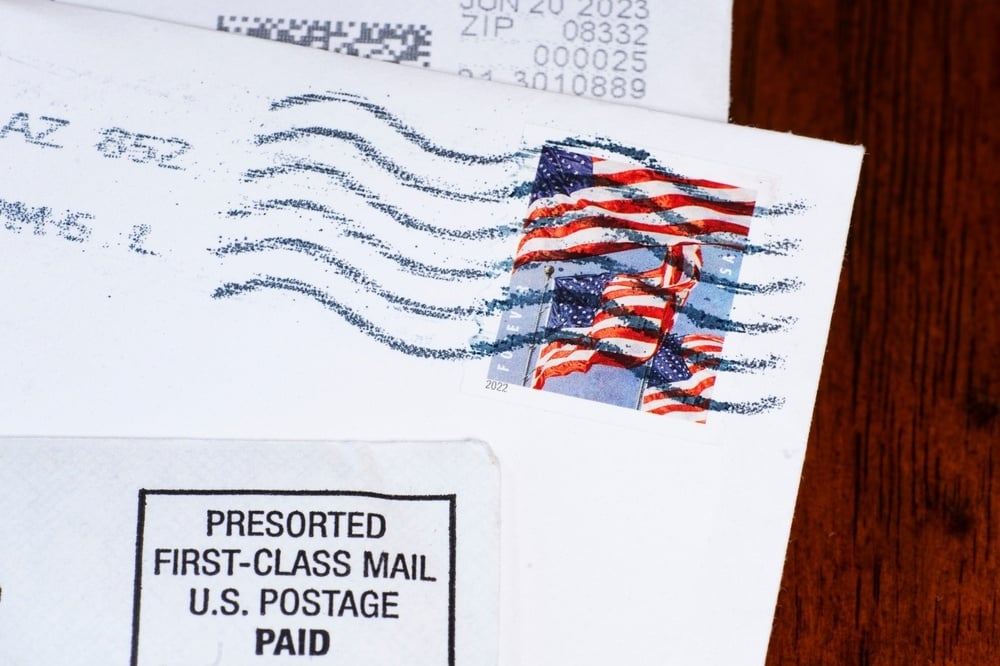 Close-up of envelope with American flag stamp and presorted first-class mail label