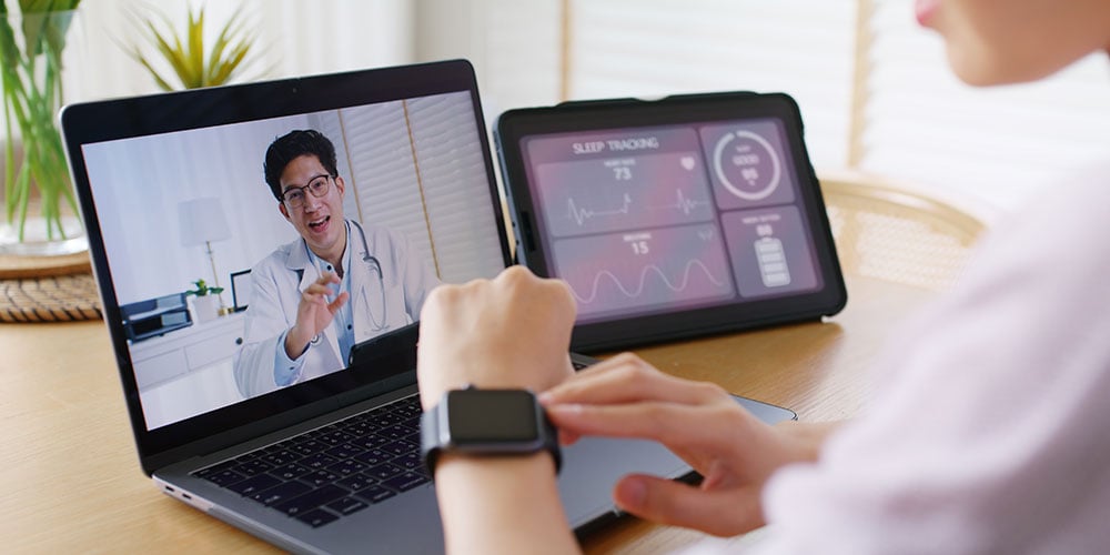 Patient using smartwatch during virtual healthcare appointment with doctor, with tablet displaying sleep tracking data.