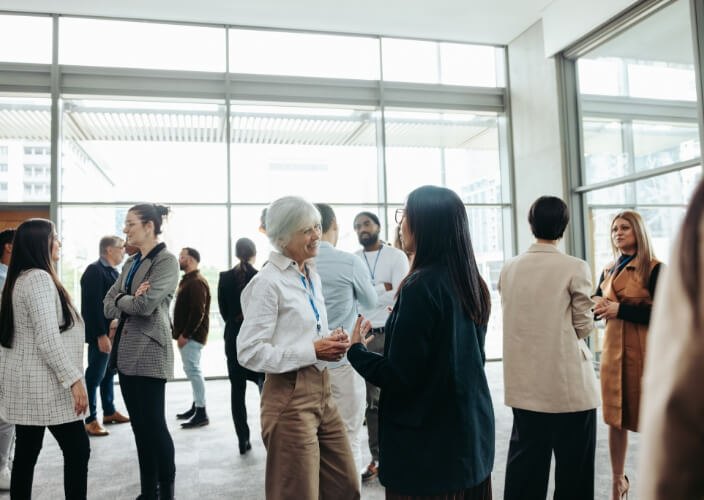 Group of people networking and talking inside a bright, modern conference space.