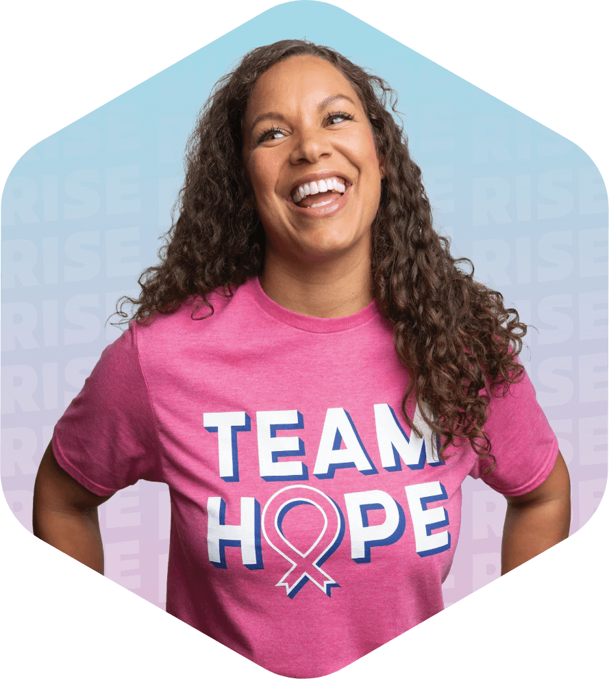 Smiling woman wearing a pink 'Team Hope' t-shirt with a background displaying the word 'Rise' repeatedly.